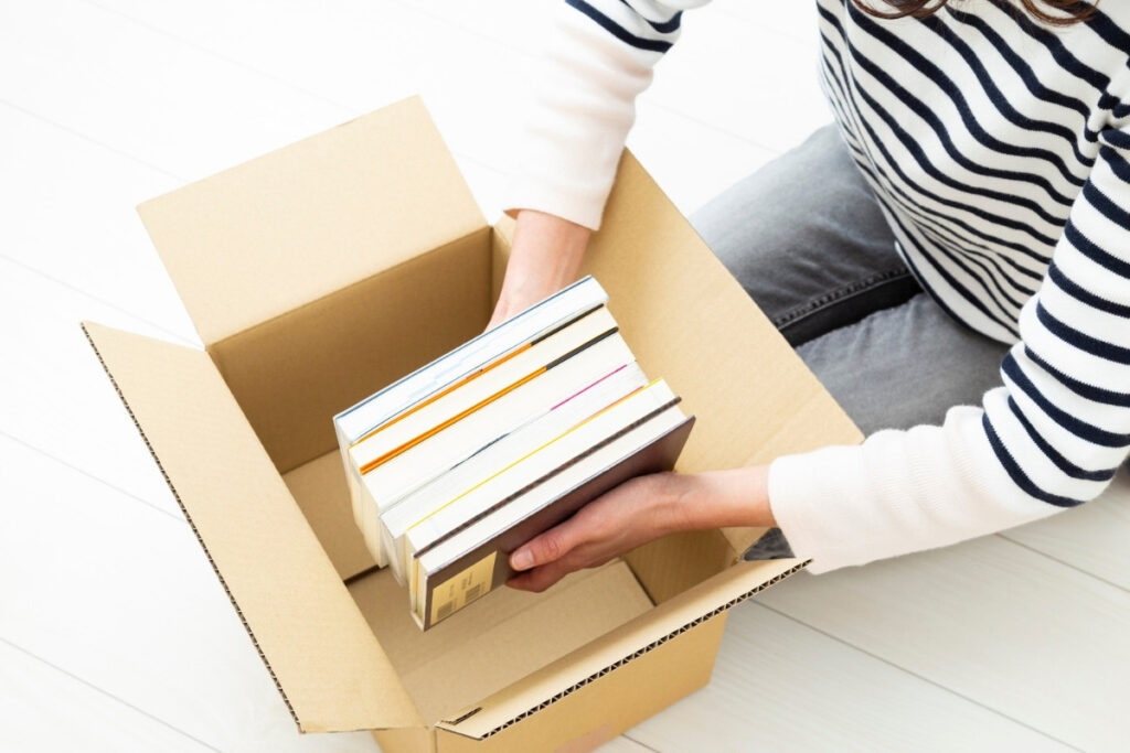 Packing books neatly inside a cardboard box while trying to avoid mistakes