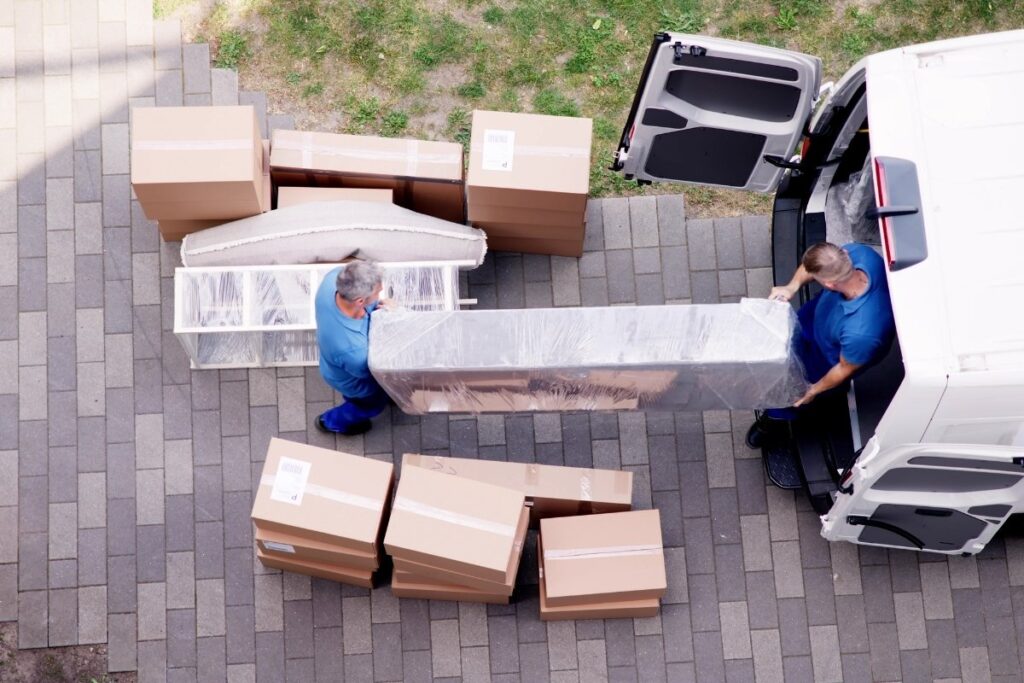 Movers loading wrapped furniture into a moving van.